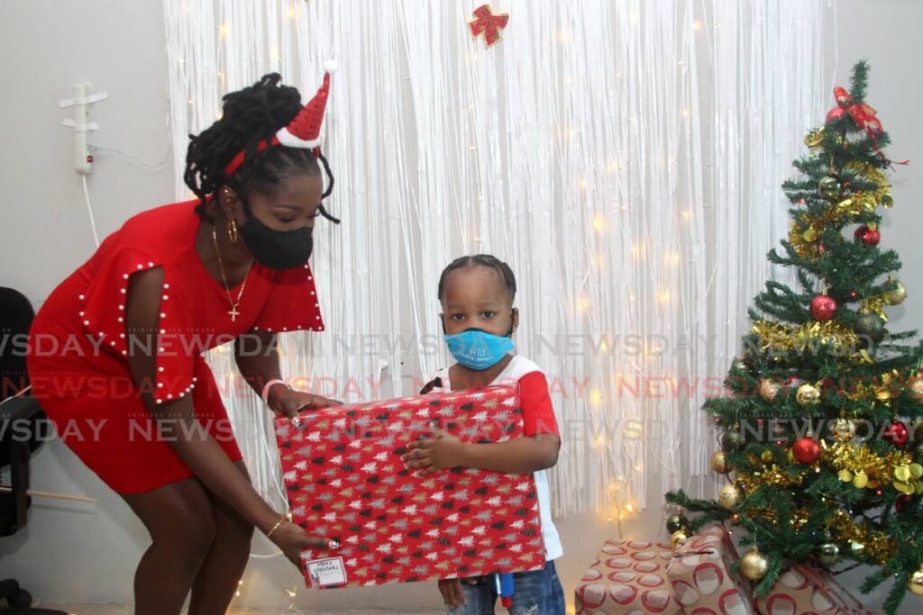 Little Christopher Babb, received his gift from councillor Joy Benjamin during the Christmas Extravaganza for the children in her electoral district of St barb Chinapoo on Thursday. Photo by Roger 