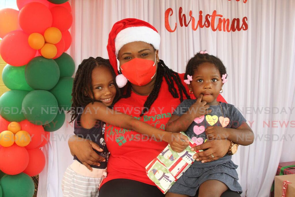 Councillor for Cap-de-Ville/Fanny Village Bryana Fortune-John is embraced by two of the children who attended her Christmas extravanza, where the children were treated with  gifts on Friday. - Marvin Hamilton
