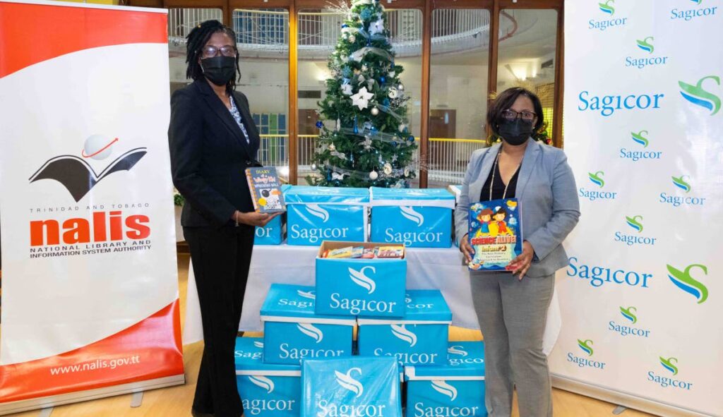 Michelle Bell-Sookhoo, right, vice president, human resources, Sagicor Life Inc, hands over the books donated by Sagicor team members to the library’s PR and marketing manager Debbie Goodman, at the Nalis headquarters in Port of Spain.  - 