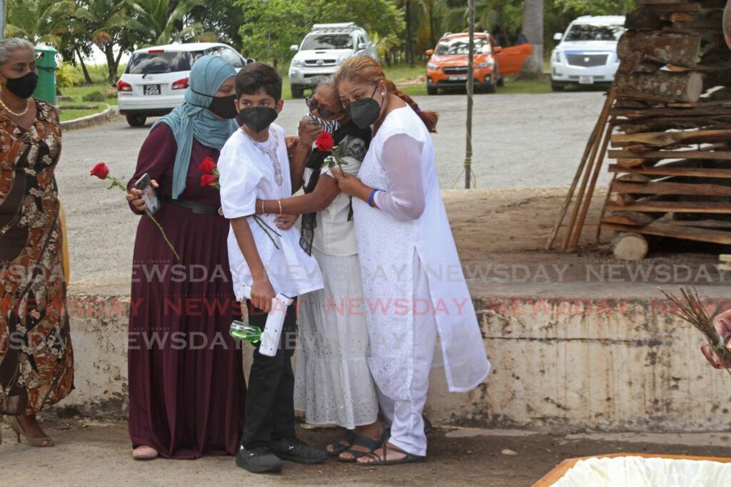 Relatives comfort the widow of Lalman Kowlessar Mary Kowlessar, second from right, before his cremation, at the Waterloss Cremation site, on Sunday. - Marvin Hamilton