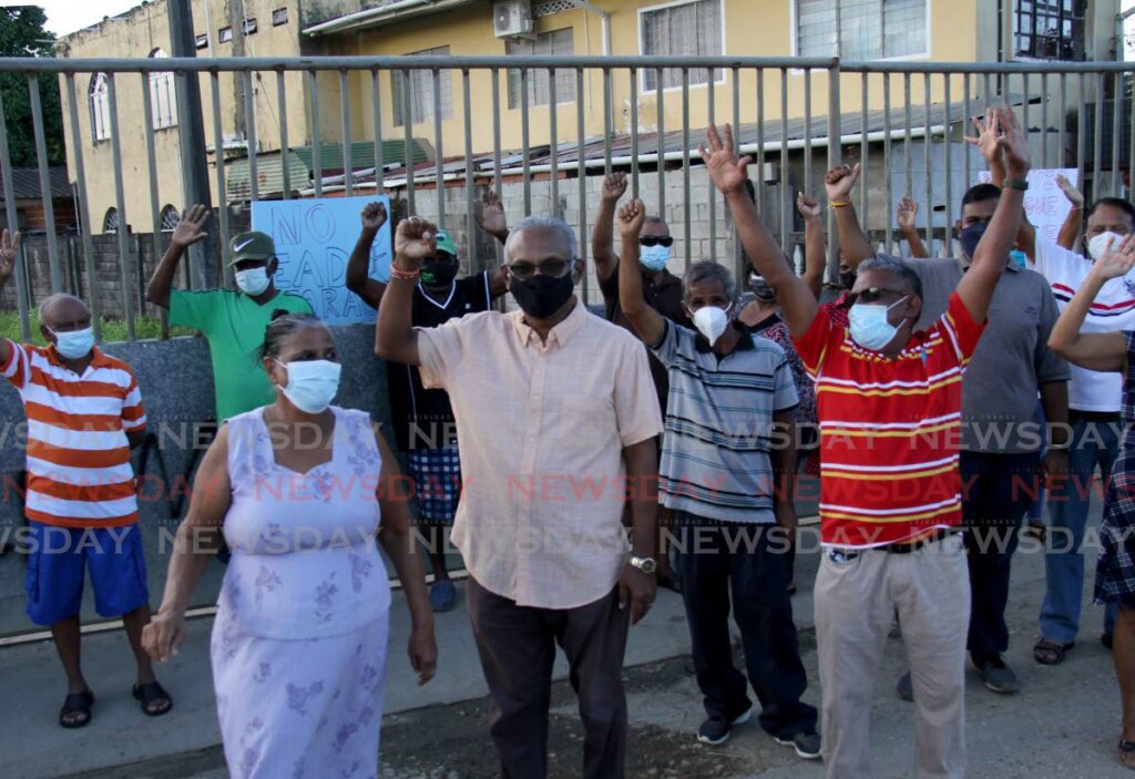 Member for Couva South Rudranath Indarsingh and residents of Beaucarro Road, Freeport in Couva raise their hands in victory as they stand outside the proposed site of a storage facility for the bodies of covid19 victims. Photo by Ayanna Kinsale