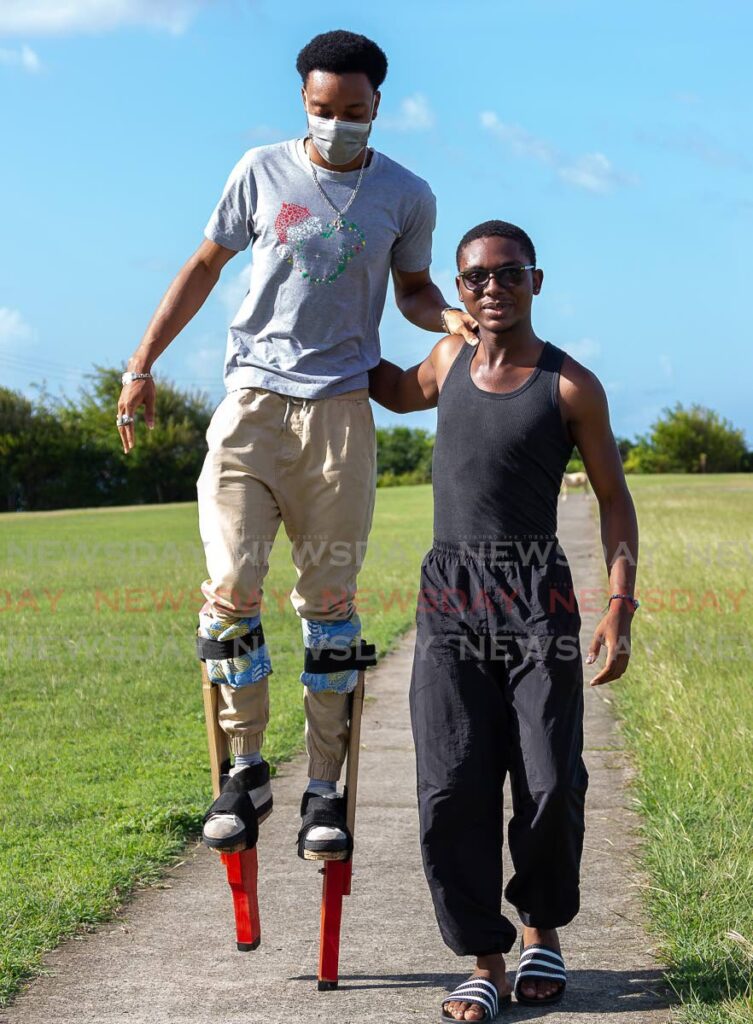 Joshua John walks on stilts for the first time while assisted by his instructor Rayon Marshall at Plymouth Grounds last month. Photo by David Reid