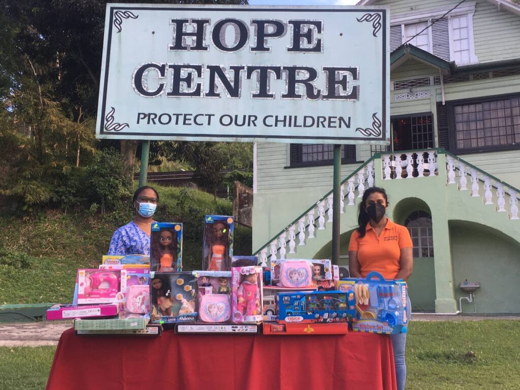 A member of the Gift for Life Foundation (right) presents a caretaker at the Hope Centre in San Fernando with toys for children at the centre.  - Gift for Life Foundation
