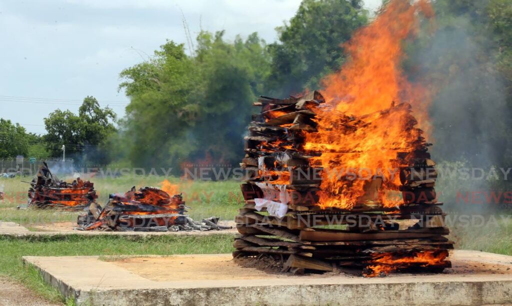 In this file photo three bodies burn on open-air pyres at the Caroni Cremation Site. 