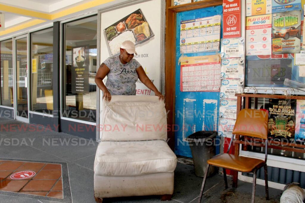 In this August 2021 file photo, a worker removes a chair from a lotto booth on Saddle Road, Maraval after it was damaged by flood water. - FILE PHOTO/AYANNA KINSALE