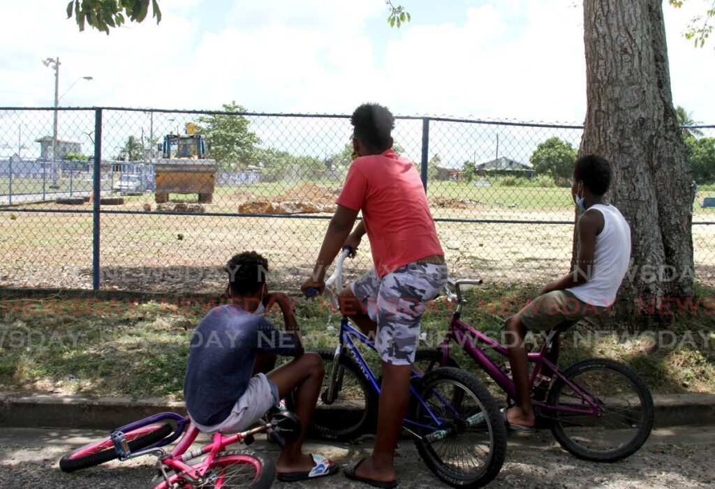 Children watch as Arima Borough Corporation workers clear debris of a facility in Malabar. The Division of Gender and Child Affairs on Friday launched the National Children's Registry. - File photo