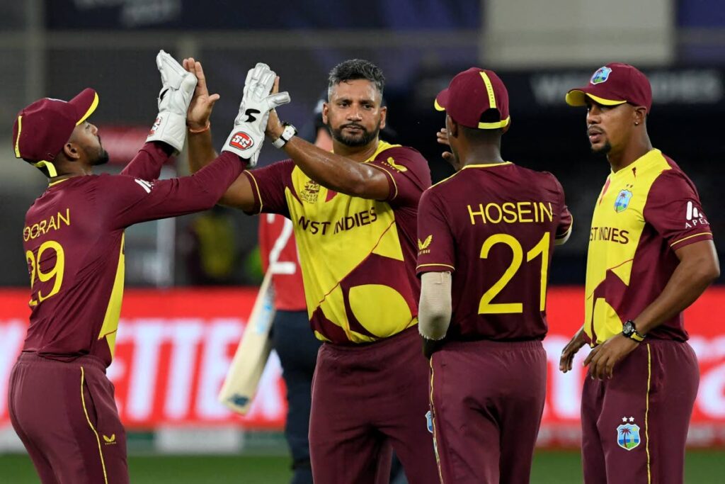 West Indies' players (left-right) Nicholas Pooran, Ravi Rampaul, Akeal Hosein and Lendl Simmons celebrate the dismissal of England's Jason Roy (not pictured) during the ICC Twenty20 World Cup match between England and West Indies at the Dubai International Cricket Stadium in Dubai, UAE on October 23, 2021.  - 