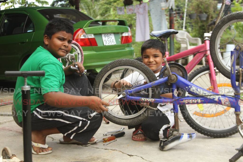 Riad, left, and Sheraz Ali work as a team to repair bikes at their home in Sobo Village, La Brea. - Photo by Marvin Hamilton
