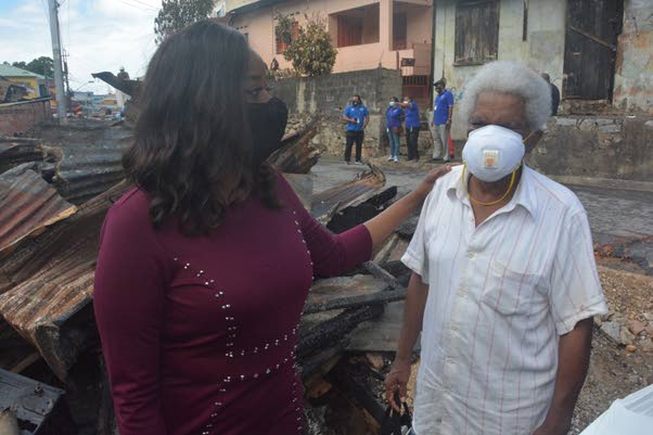 Social Development Minister Donna Cox consoles Renwick Douglas whose home at Quarry Street, Belmont was destroyed in a fire caused by fireworks on January 1.  - 