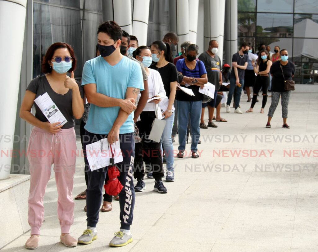 People wait in line to get their booster shot at the vaccination site at Southern Academy for the Performing Arts (SAPA), San Fernando. Photo by Ayanna Kinsale