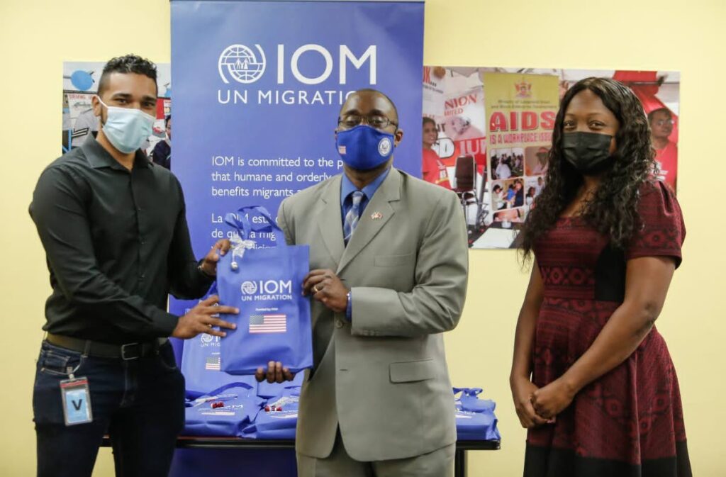 US Embassy in Port of Spain Chargé d'Affaires Shante Moore (centre) and Head of the International Organization for Migration Port of Spain office Jewel Ali hand over a tablet to Catholic Commission for Social Justice (CCSJ) representative Darrion Narine at an event at the UN House in Port of Spain on December 30. - International Organization for Migration (IMO) Port of Spain Office