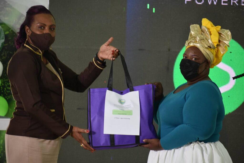 Shelly-Ann Baptiste, left, manager, THA Business Development Unit presents Khanica Murray with a prize from bmobile for winning the agro processing category at a virtual business expo. - 