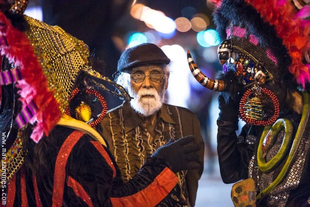 Traditional mas veteran Narrie Approo stands among Black Indian masqueraders. Approo died on Thursday at 94. Photo courtesy Maria Nunes - 