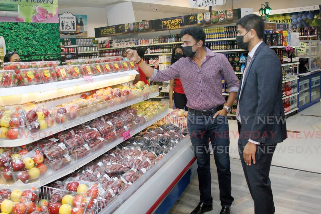 Chaguanas Chamber of Commerce president Richie Sookhai, left, and Supermarket Association of TT president Rajiv Diptee examine the prices of imported fruits at Xtra Foods supermarket, in Chaguanas on Saturday. - Photo by Lincoln Holder