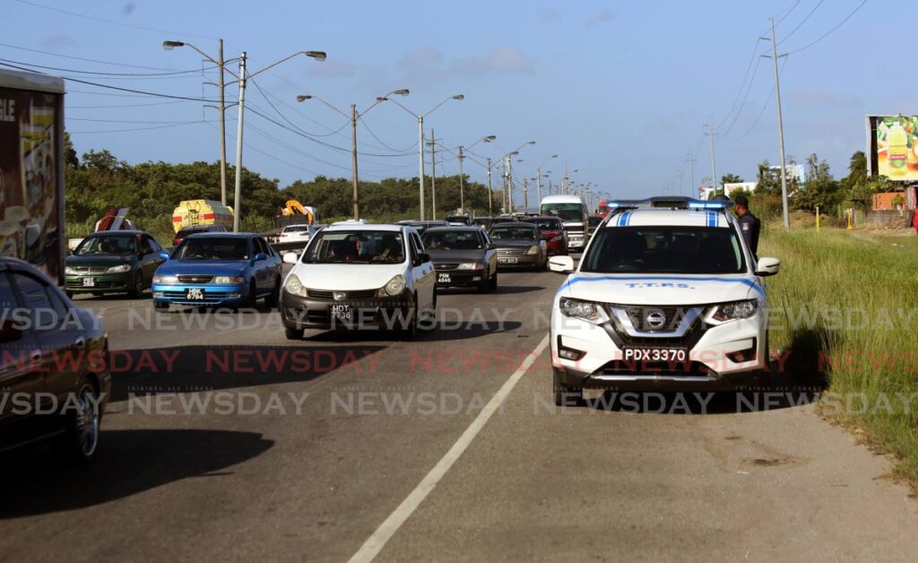 Police monitor traffic on the Beetham Highway on Monday morning after residents earlier blocked the roadway with burning debris. - SUREASH CHOLAI