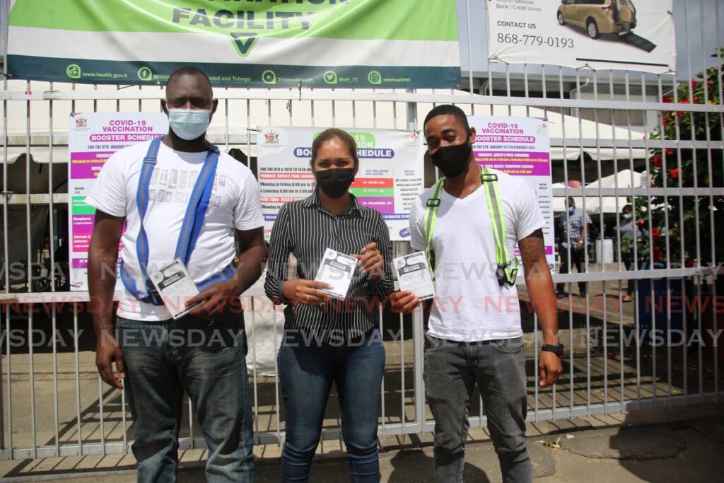Construction workers, from left, Garvin Gould, Carissa Narine and Oronde Gooding show off their vaccination cards after receiving booster shots of a covid19 vaccine at the Paddock, Queen's Park Savannah, Port of Spain, Monday. - SUREASH CHOLAI