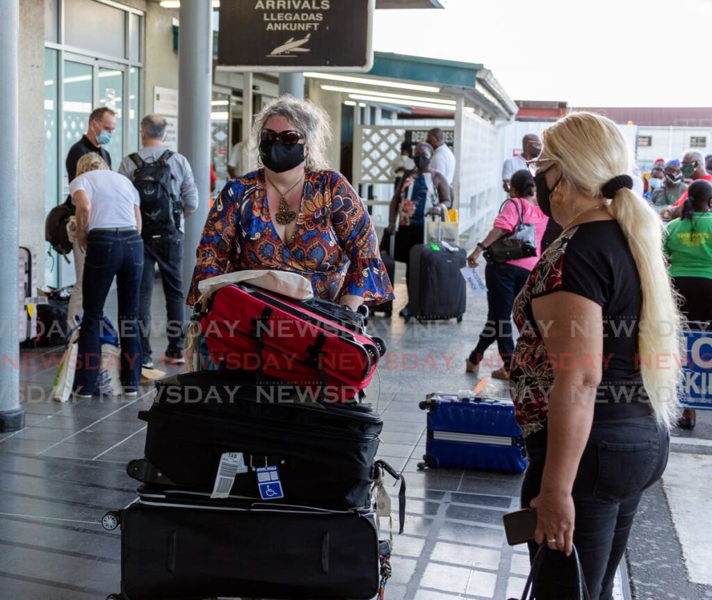 UK visitor Sue Jones, front, walks with her suitcases after arriving in Tobago on Monday aboard British Airways.
  - David Reid