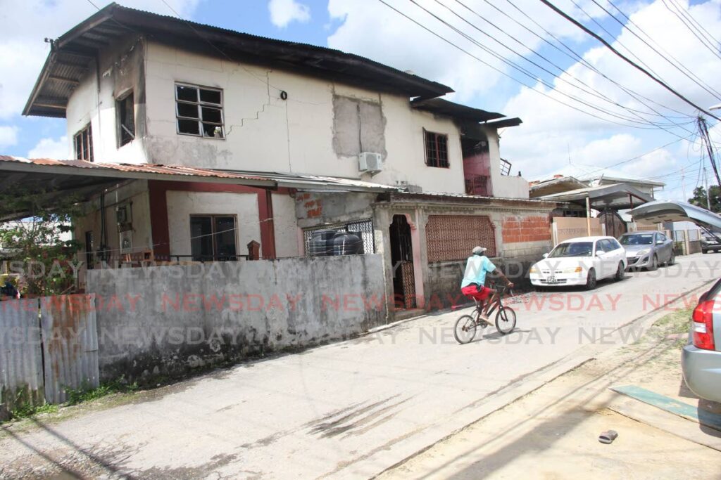 A man rides a bike outside  the burnt out home along Orange Field road, Chase village Chaguanas which left nine people homeless - Lincoln Holder