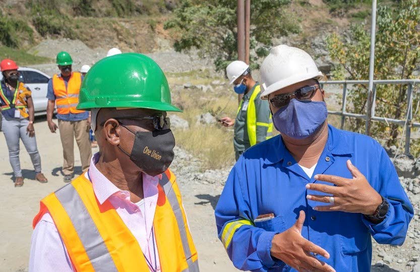 Secretary of Infrastructure, Quarries and Urban Development Trevor James, left, chats with mobile fleet engineer Keron George about the operations at Studley Park Quarry during a site visit last Thursday . - THA