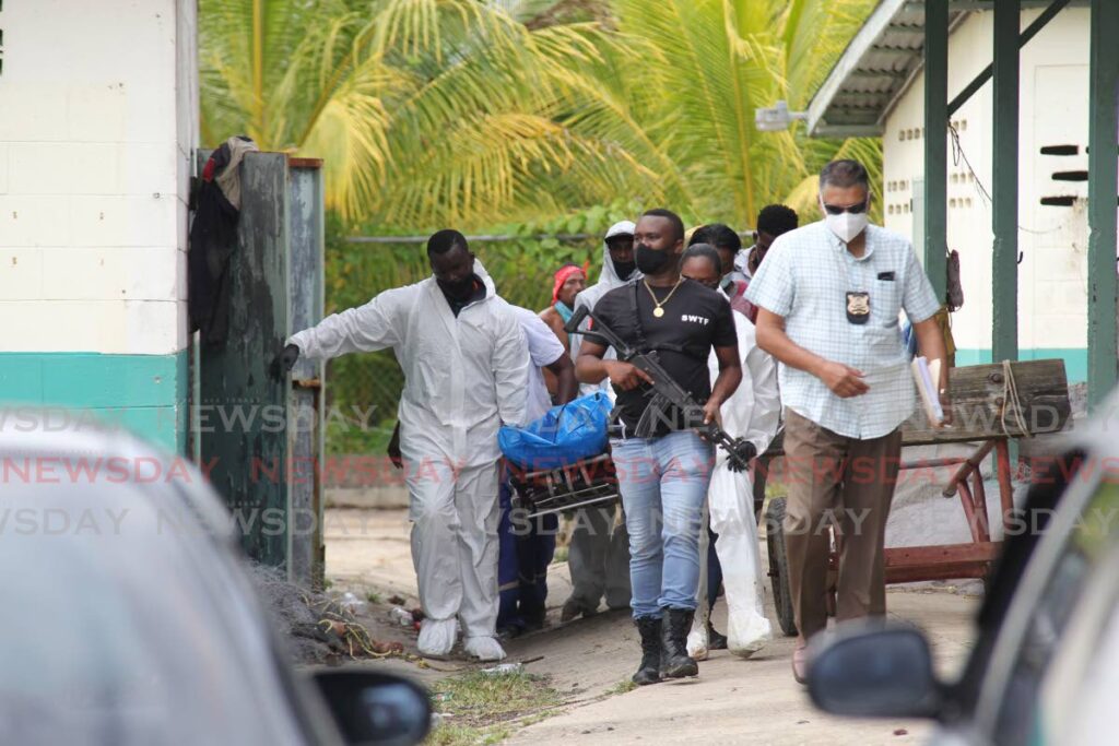 Undertakers remove the body of Demaine Benjamin who was shot and killed at the Erin beach fishing depot on Thursday. Two other people were wounded in the attack and are at hospital. - Lincoln Holder