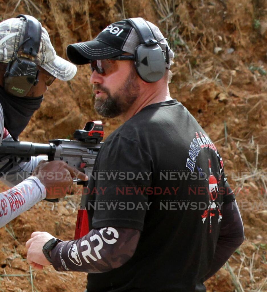 Train, Evolve and Compete shooting tournament match director Brendon Souder, right, stands next to a trainee at the MH Tactical Shooting Range in Chaguaramas on Thursday. - Angelo Marcelle