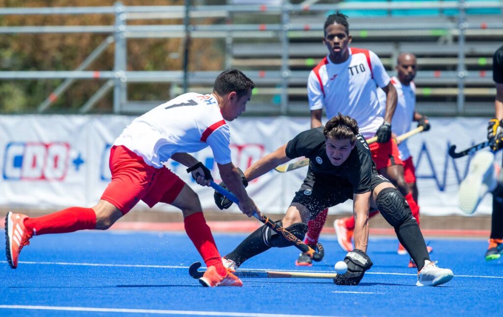 Trinidad and Tobago's Jordan Vieira (L) and Canada's Brendan Guraliuk (C) battle for the ball during the Pan American Cup hockey match, on Monday, in Santiago, Chile. Canada won 5-2. - via Pan American Hoceky Federation
