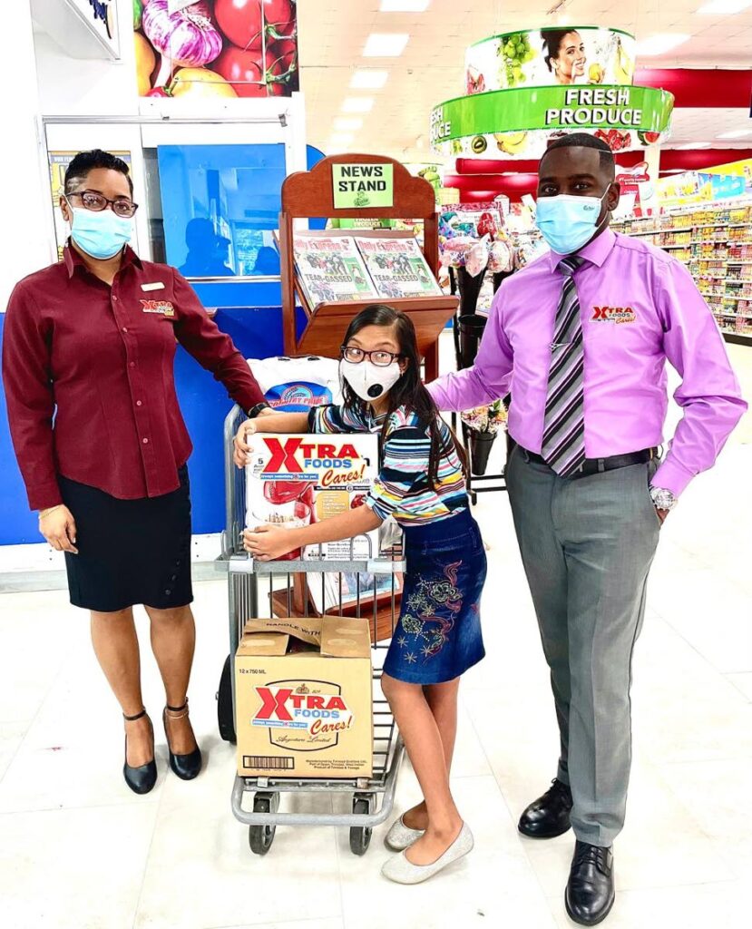 HELPING HAND: Young baker Rochelle Persad, 12, receives baking items from Xtra Foods Ltd's marketing manager Daniel Austin and Xtra Foods' Sangre Grande branch's CSR Mrs Cyril. PHOTO COURTESY XTRA FOODS 