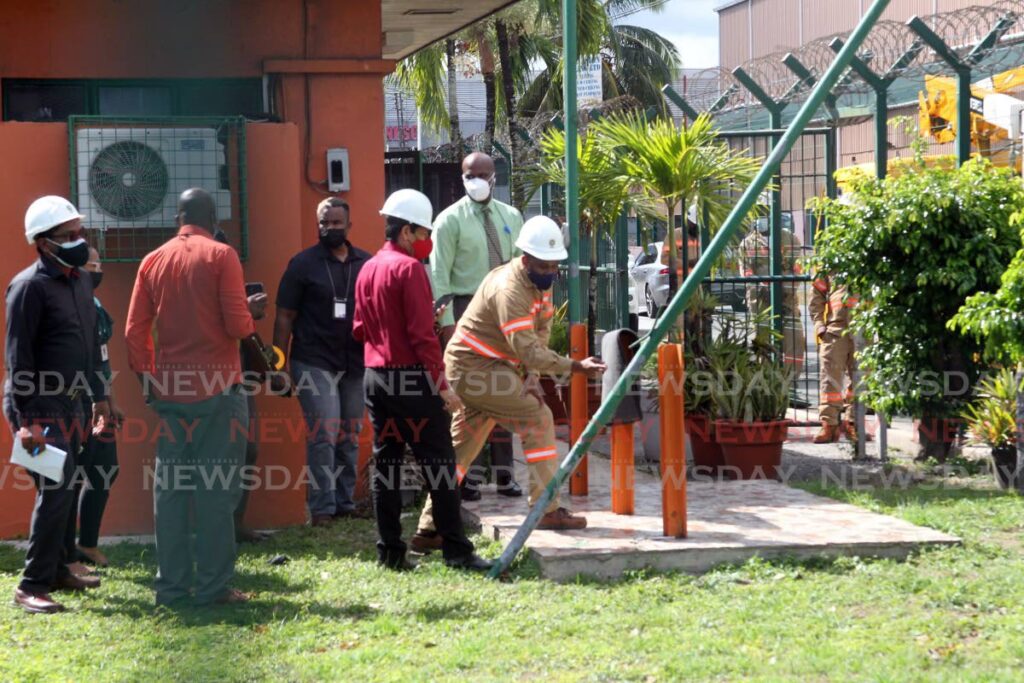 TTEC officials examine a flag pole that came into contact with an electrical wire outside the Civilian Conservation Corps office at Woodford lodge, Chaguanas. One person was killed and three injured in the accident. - Lincoln Holder