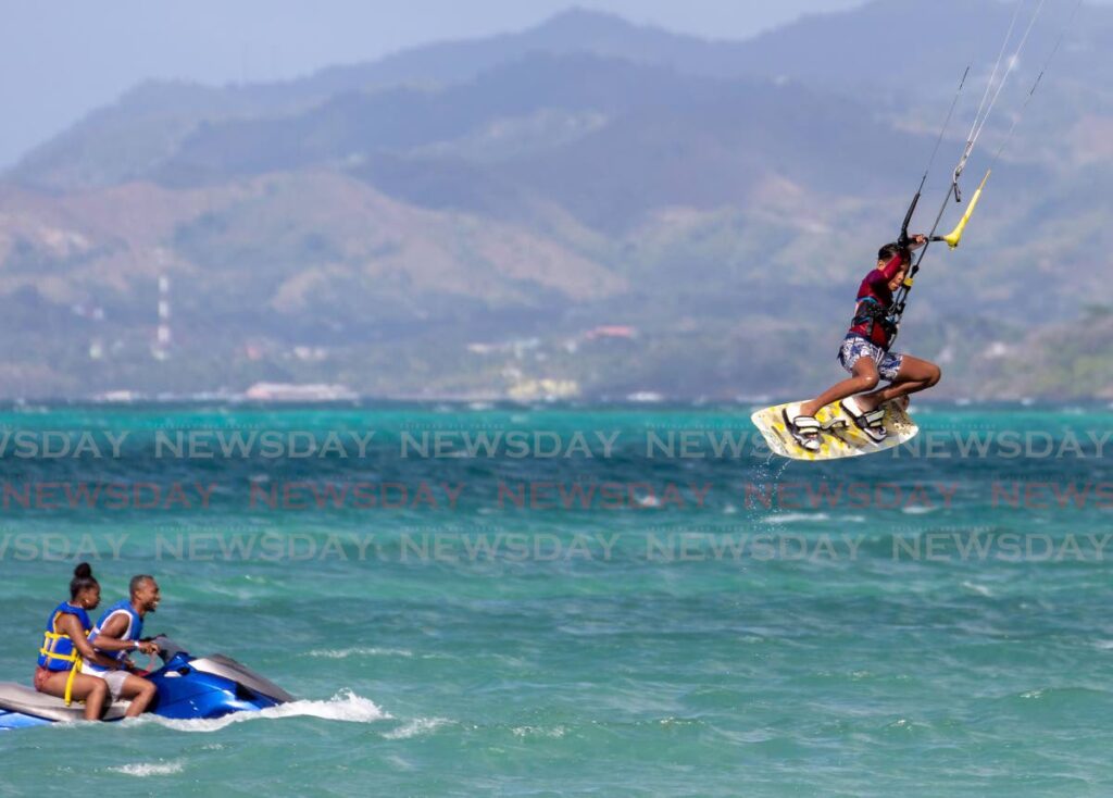 A youngster shows off his kitesurfing skills at Pigeon Point Beach as two people pass nearby on a jet ski. FILE PHOTO - 