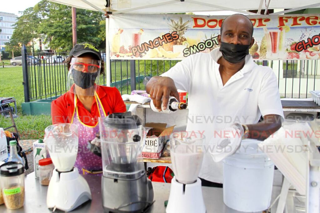 FILE PHOTO: Michael Williams, right, and his sales assistant at his Doctor Fresh food stall on the track at the Queen's Park Savannah, Port of Spain, on July 30, 2021.