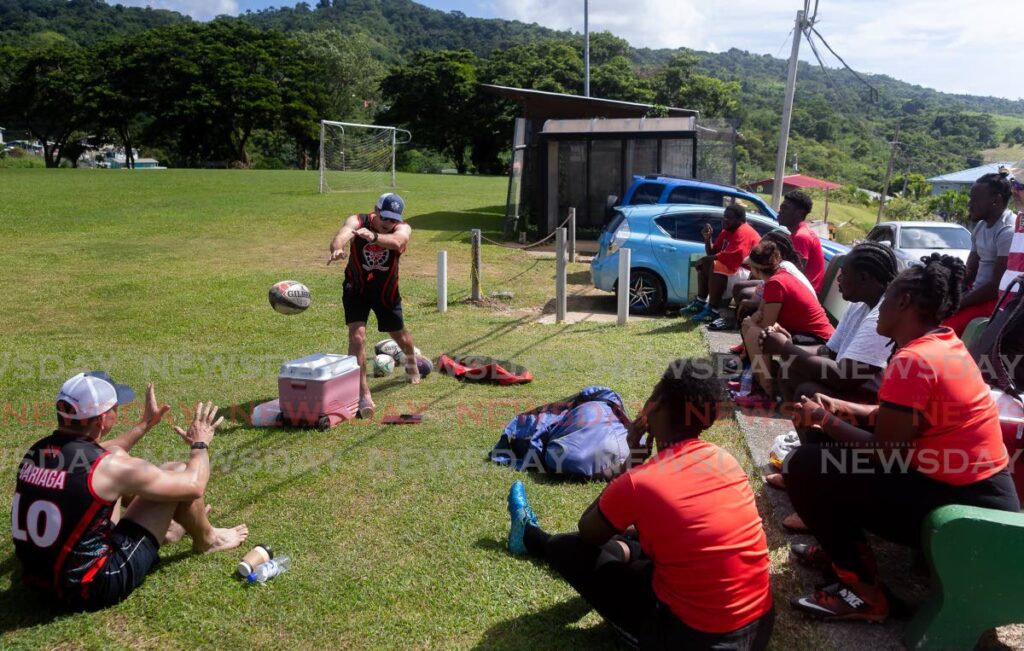 In this November 6, 2021 file photo, rugby coach Robin Mac Dowell of Canada (second from left) and Colton Cariaga of the United States, demonstrate a throw and catch technique to members of the Tobago Rugby Football Club, at the Calder Hall recreation field. - David Reid