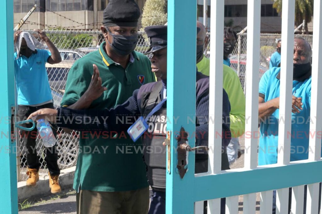 In this file photo, a WASA security officer locks out protesting workers at the company's St Joseph headquarters on January 26.  - ROGER JACOB