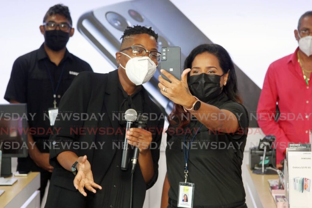 Gracia Whyte, Samsung mobile experience marketing manager, explains some of the functions of the S21 FE 5G smartphone at the launch of the device on the local market at the Samsung outlet at Gulf City Mall. - Lincoln Holder