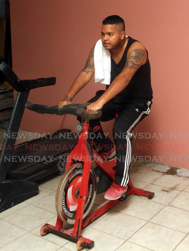 Careca Romero, aka DJ Romero, does a workout on his exercise bike at his home in Arima. - ANGELO MARCELLE