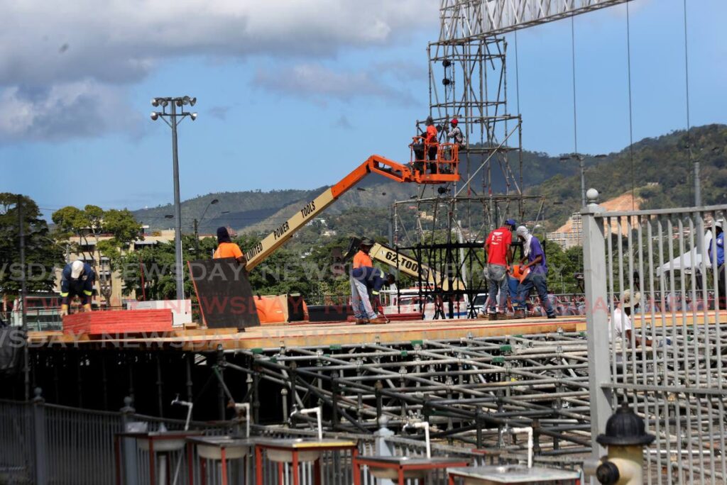 Workers install the flooring on what will be this year's Carnival stage in the front the Grand Stand at the Paddock of the Queen's Park Savannah on Friday.  - SUREASH CHOLAI