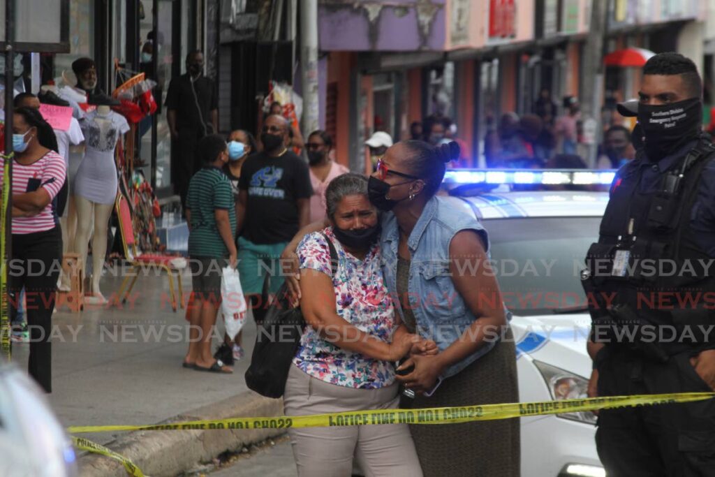 An unidentifed woman is consoled after Andy Alberto Macias Hosien, a security officer at Ketan Jewellers, was shot and killed on Saturday morning during a robbery at the jewlery store on High Street, San Fernando. - PHOTO BY MARVIN HAMILTON