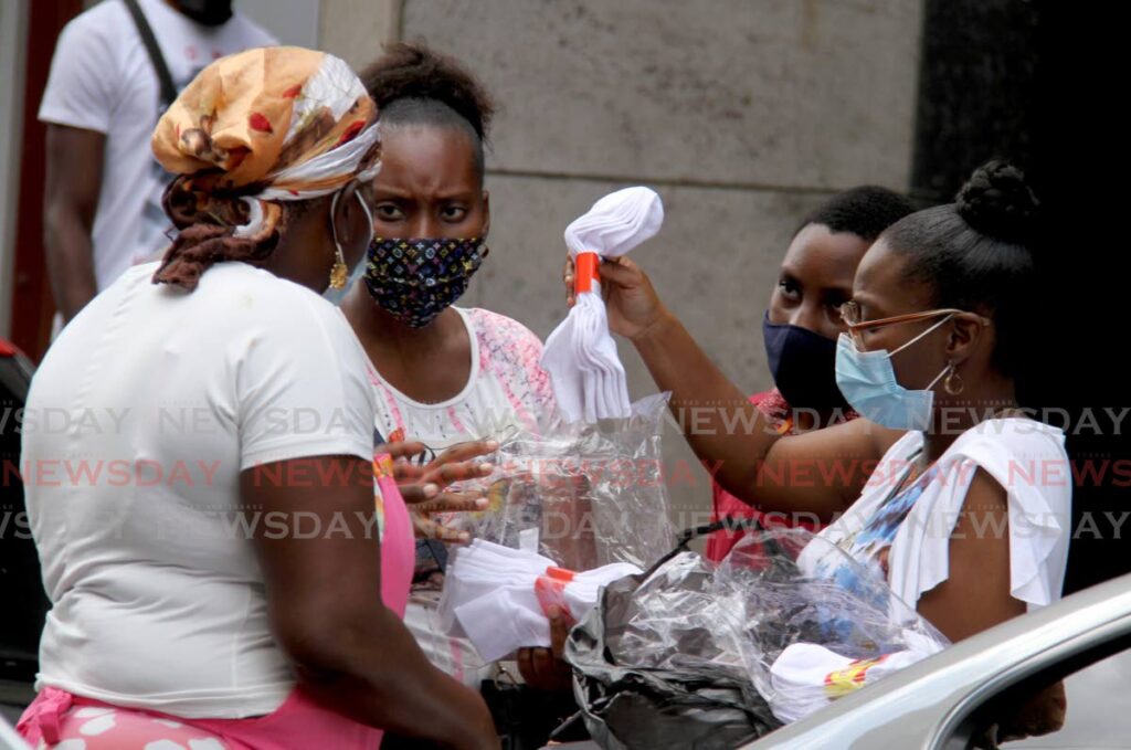 Customers buy school socks from a vendor on Henry Street, Port of Spain who did brisk sales on Saturday as parents shopped for back-to-school items for students in forms one-three and standard five who begin the return to in-person classes from Monday. - AYANNA KINSALE