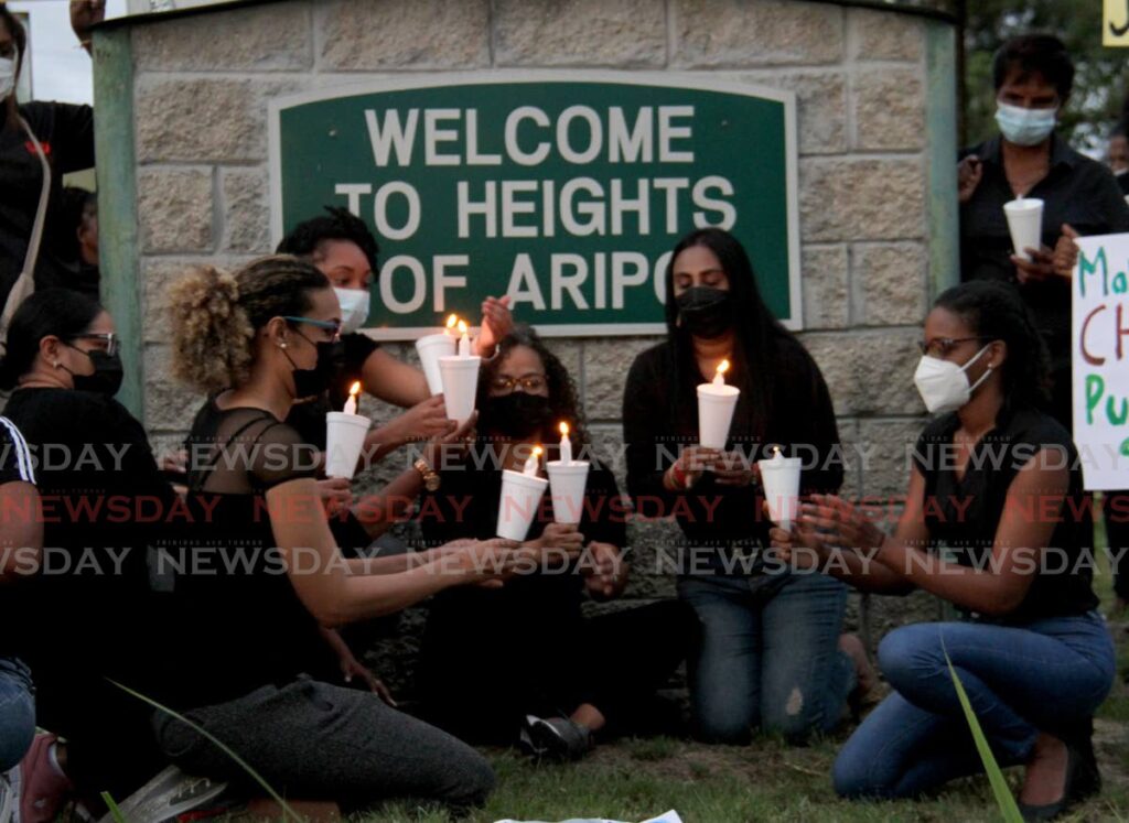 St Augustine MP Khadijah Ameen, left, and members of the UNC Women's Arm hold lit candles for murdered women during a vigil at Heights of Aripo, Arima on Saturday. - AYANNA KINSALE