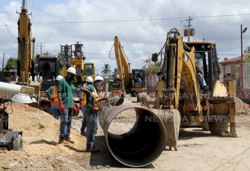 A WASA employee uses a power saw to cut a cylindrical pipeline as work continues to repair a ruptured sewere pipeline at Beetham Gardens, Port of Spain, on Monday. Photo by Ayanna Kinsale
