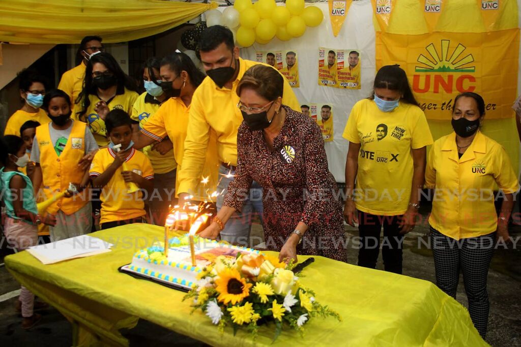 UNC leader Kamla Persad-Bissessar, centre, cuts a victory cake with Debe South Councillor-elect Khemraj Seecharan at a UNC political meeting on Monday night. - ROGER JACOB