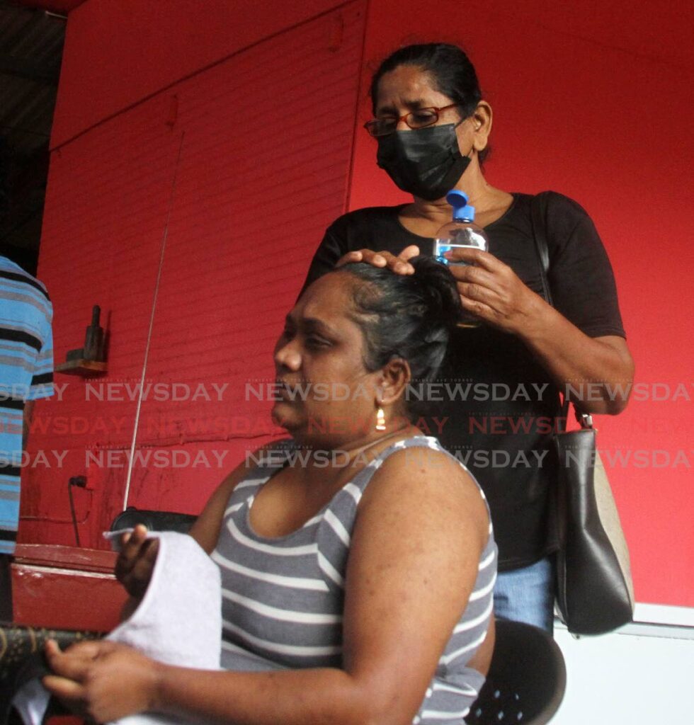 Bibi Ameena Laloon, mother of five-year-old Krystal Laloon, is comforted by a family friend at their Sangre Grande, Sangre Chiquito home on Tuesday.  - Angelo Marcelle
