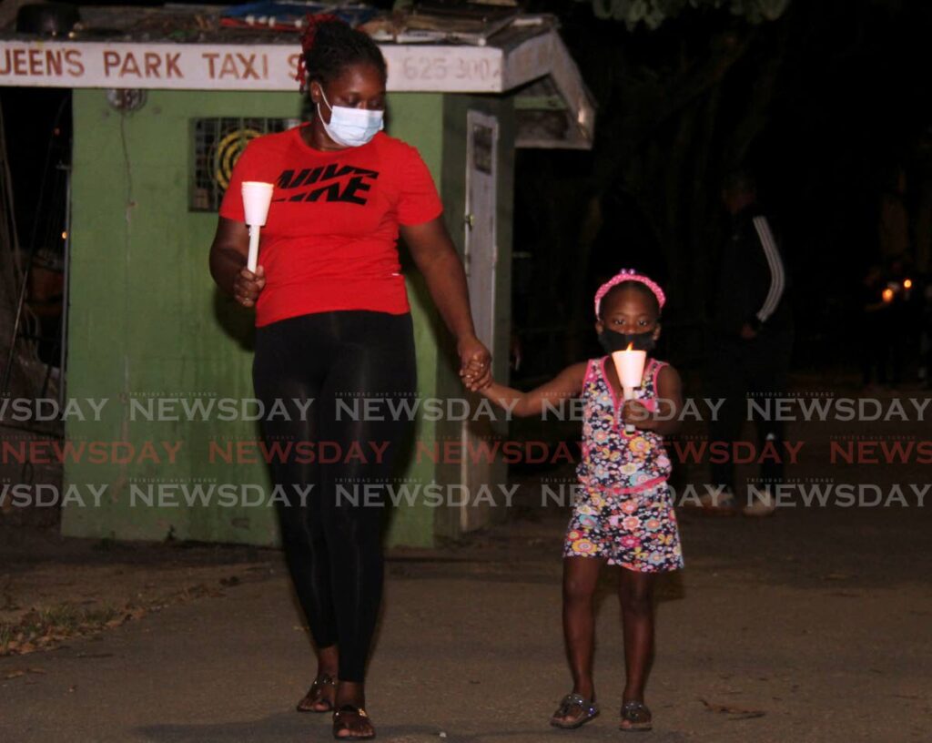 Aunt of murder victim Keithisha Cudjoe, Ziana Cudjoe-Chadee, holds her niece Zora Chadee's hand as they walk around the Queen's Park Savannah during a candlelight vigil in memory of Cudjoe on Tuesday evening. - AYANNA KINSALE