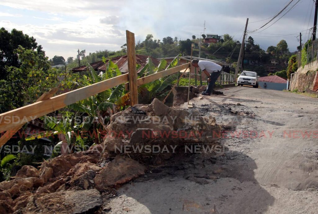 A WASA worker examines damaged water pipelines caused by works to repair a railing that was destroyed when Crystal George lost control of her car and crashed through it,  killing her, and causing serious injuries to her daughter who was in the car on Febuary 1. - SUREASH CHOLAI