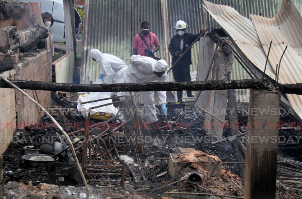 Undertakers remove the remains of couple Ramdaye and Doodooman Sankar after their St Julien Road, Princes Town home was burnt to the ground on Sunday morning. - Photo by Ayanna Kinsale