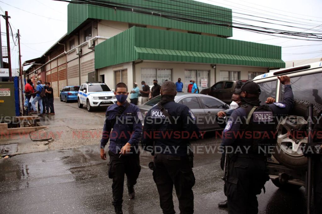 Police officers at the compound in El Socorro where four businessplaces were attacked by a gang of bandits on Tuesday. PHOTO BY SUREASH CHOLAI - 