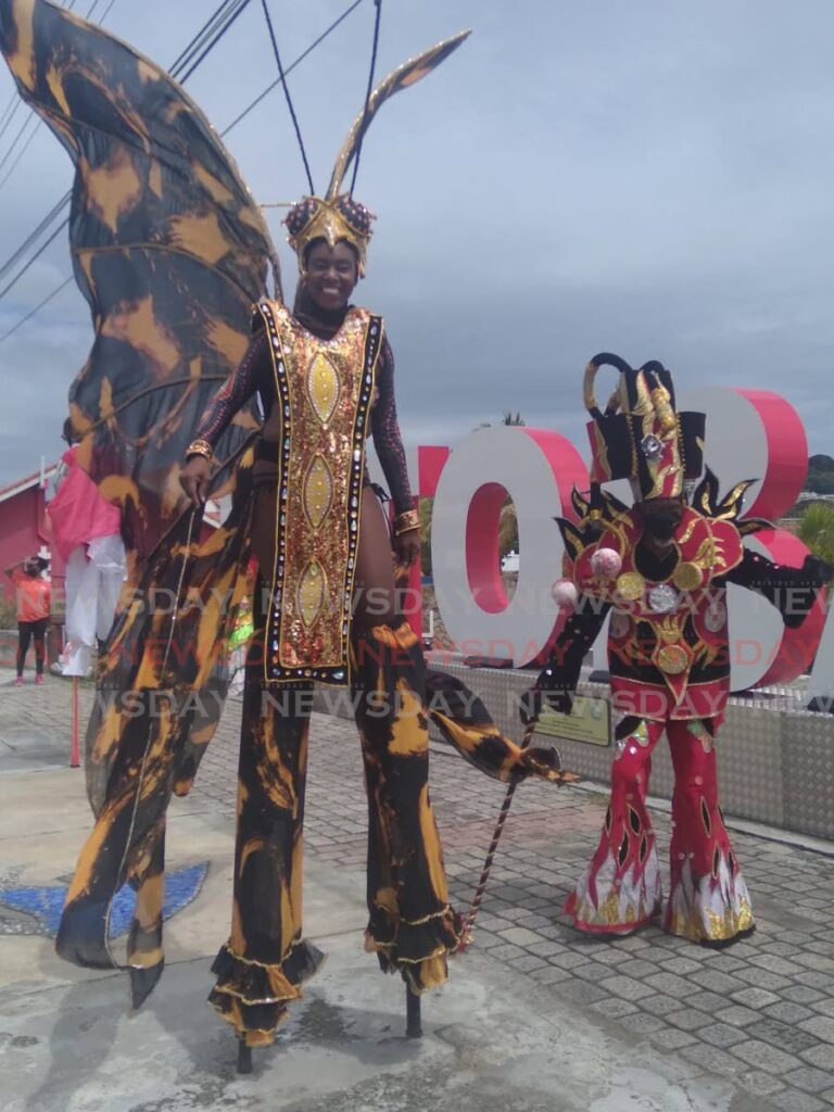Simone Scipio-Briggs, left, dances her costume, Flight of the Monarch, while Merrick Dickson portrays a fireman at the I Love You Tobago gateway sign. Photo by Corey Connelly