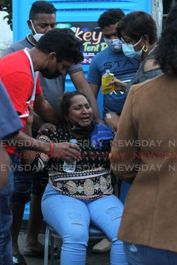 Vanessa Kussie, the wife of one of the divers, is attended to after hearing that three of the four bodies had been recovered.  Photo by Roger Jacob