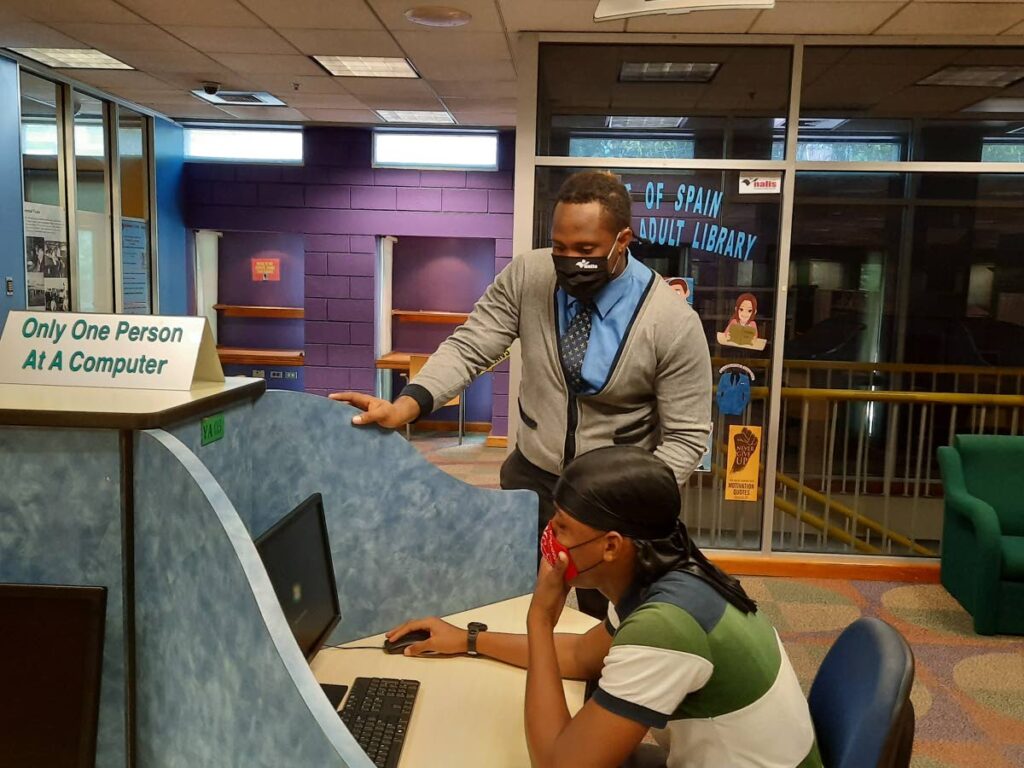 Tevin John, library assistant I, assists Michael Sayerson at the Nalis Port of Spain Young Adult Library in June 2020. Photo courtesy Nalis.
  - 