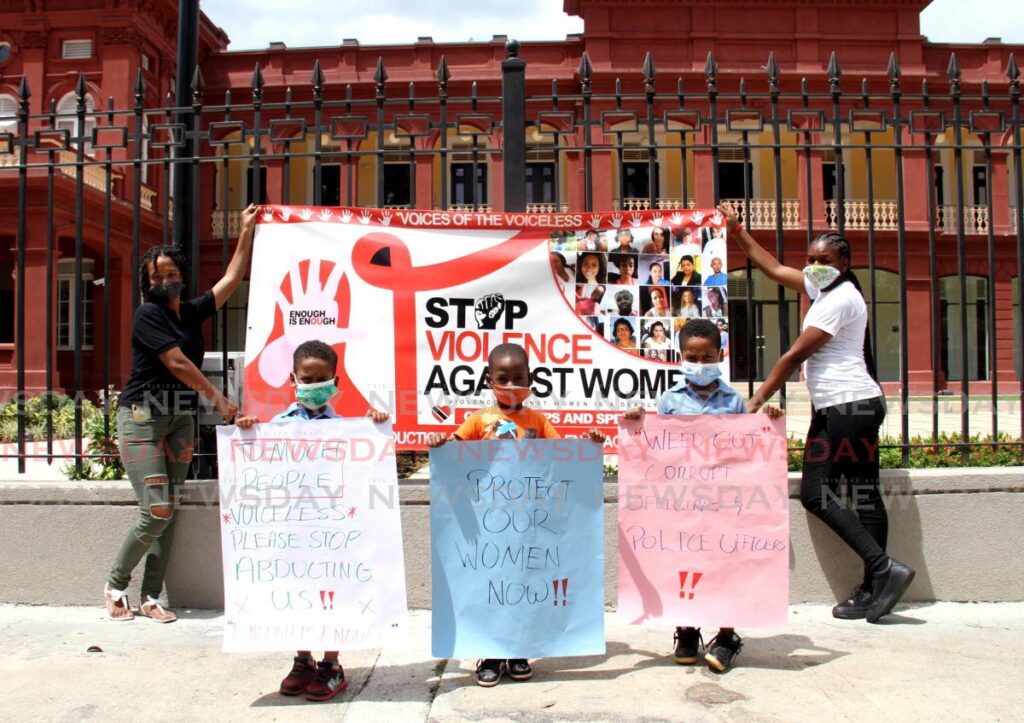 From left, Adan Nash, Jaedon Forde, and Amiel Nash display signs against domestic violence towards women outside the Red House, Port of Spain on February 27, 2021.  - Ayanna Kinsale