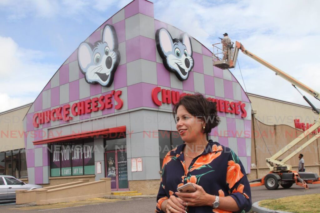 Joanna Rostant, director of YAY Entertainment, discusses the reopening of Chuck E Cheese while a worker powerwashes the entertainment centre in Brentwood, Chaguanas.   - PHOTO BY MARVIN HAMILTON